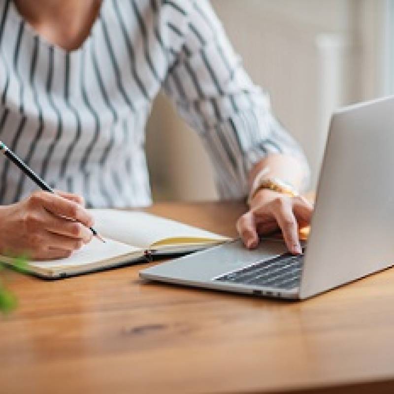 Person working on computer taking notes