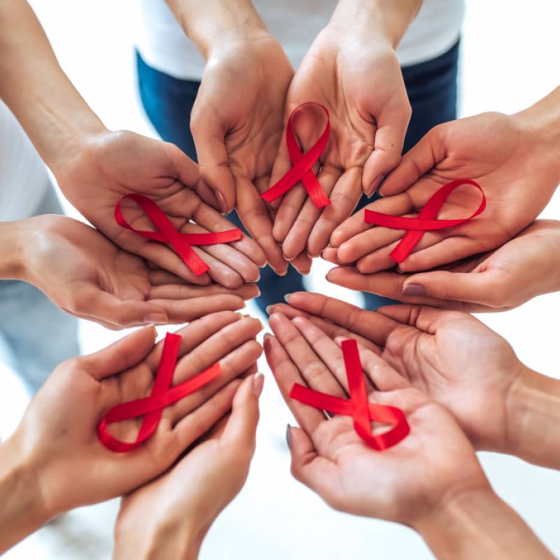 Hands in a circle each holding red ribbon