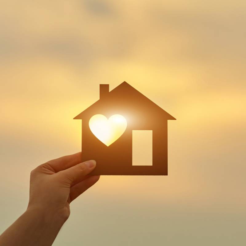 Hand holding house with a heart 