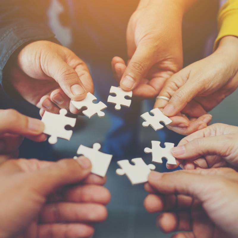 Circle of hands with people hold puzzle pieces