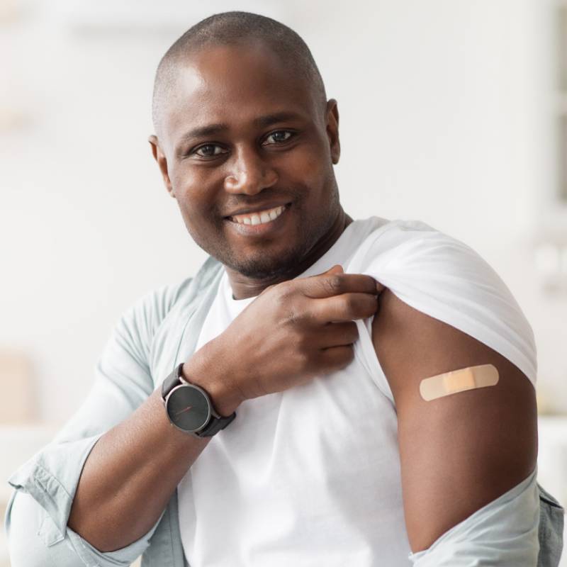 man smiling while showing the bandaid on his arm
