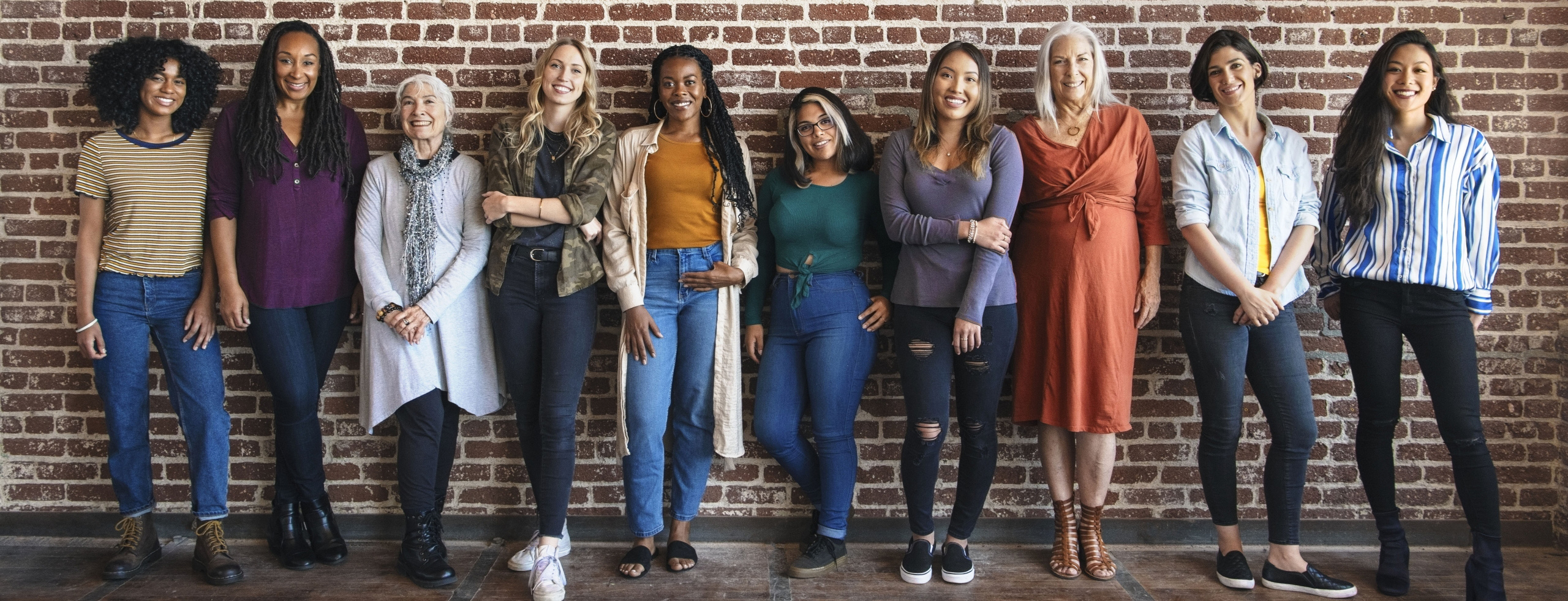 Group of ten women against brick wall