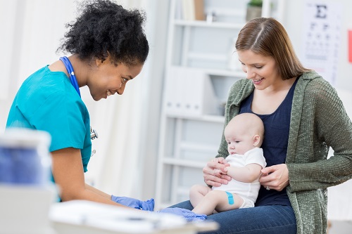 Mother holding baby during medical checkup