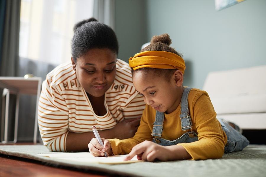 Mother helping duaghter write