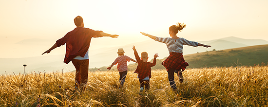 Family running through a field at sunset