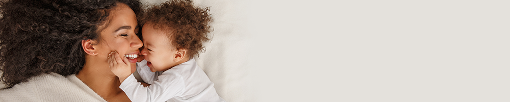 Smiling toddler holding her smiling mothers face