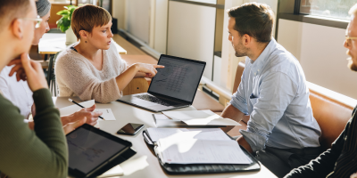 adults sitting around table looking at a computer