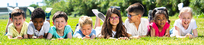 Team of friends children resting on grass together in park
