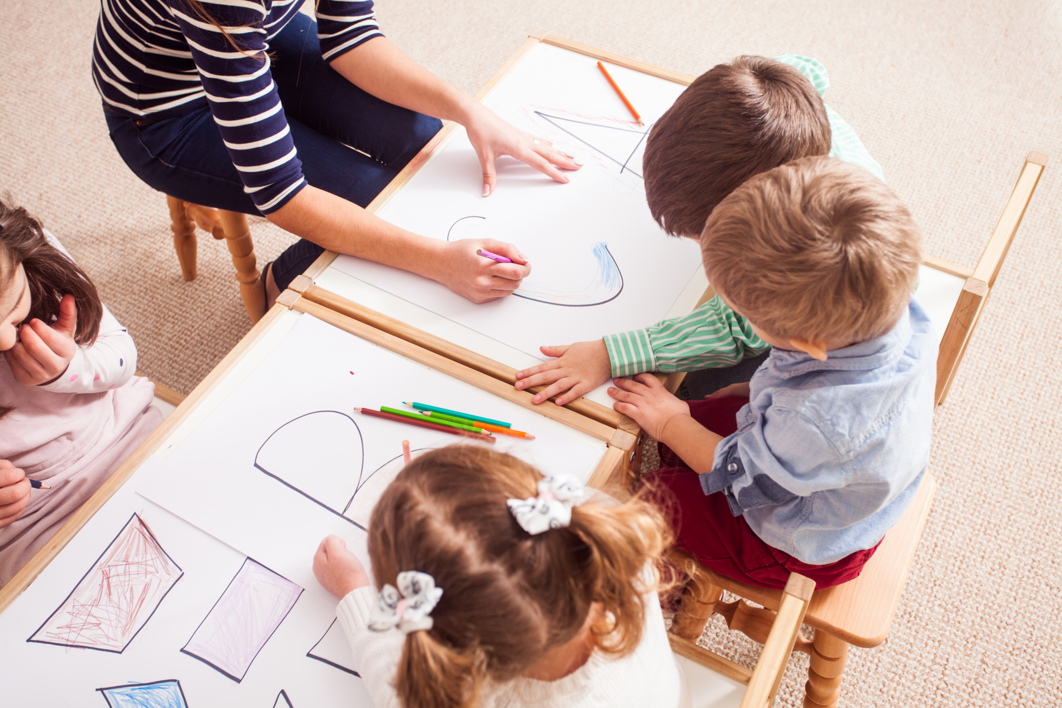 preschool children color with a teacher
