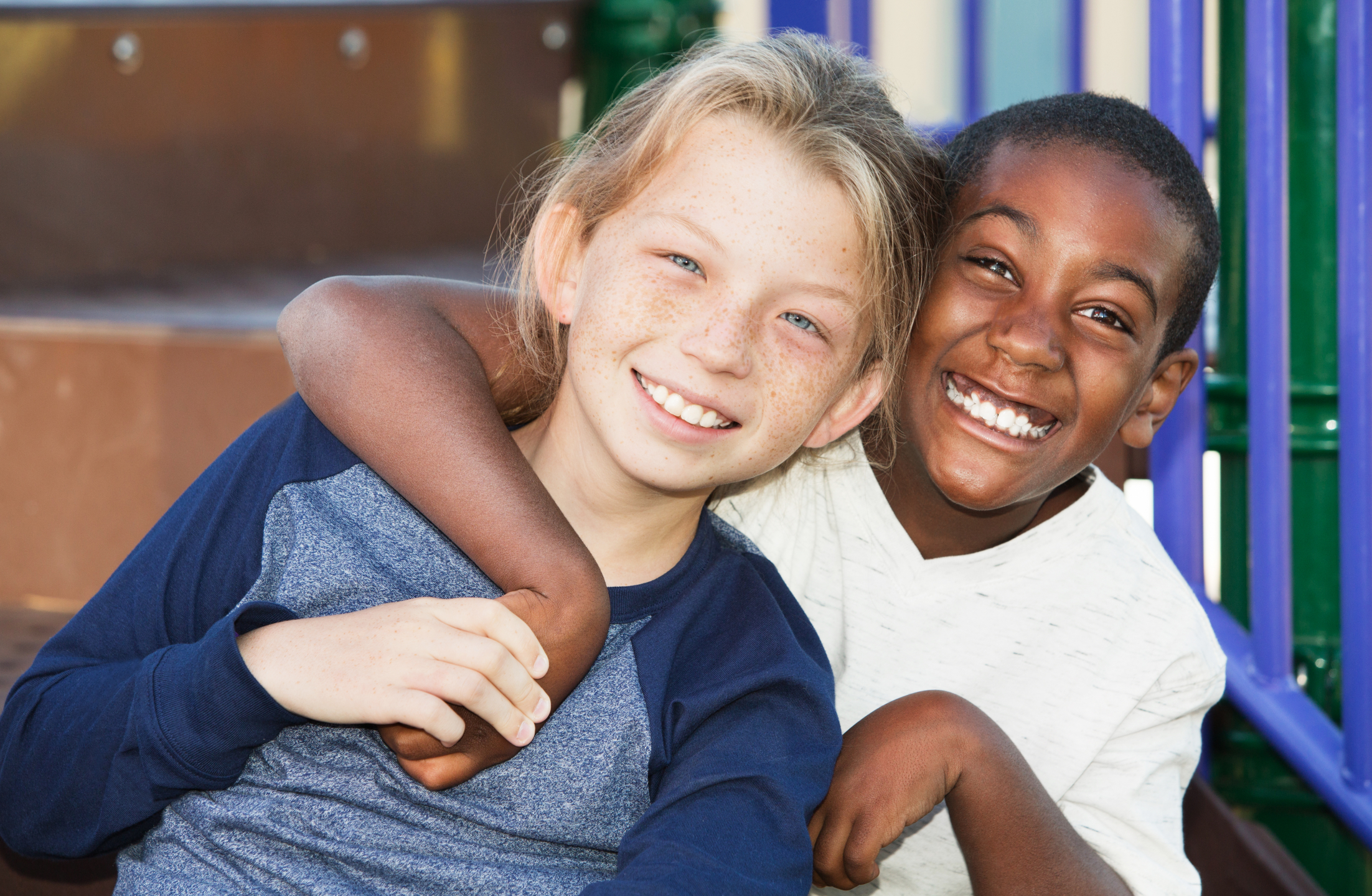 two children pose smiling on a playground