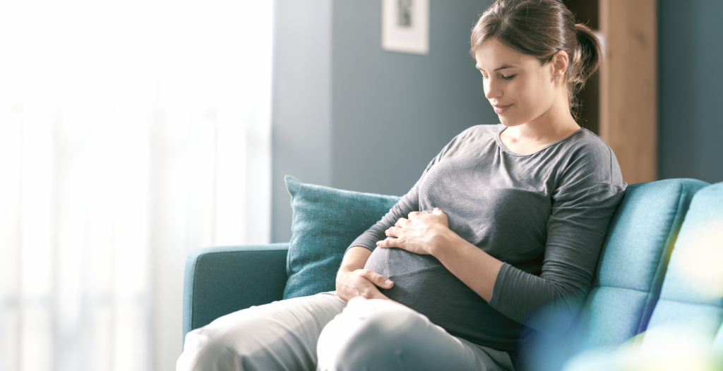 pregnant mom sitting on couch with hands on her stomach