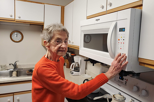 Woman with low vision using the microwave with tactile dots.
