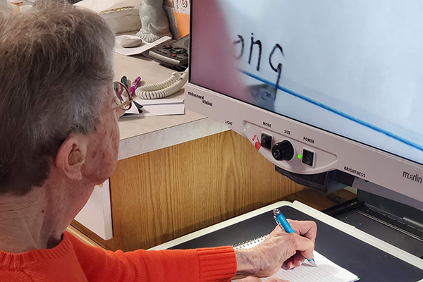 Woman using a video magnifier to write.