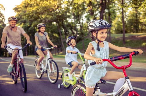 two adults and two children riding bikes while wearing helmets