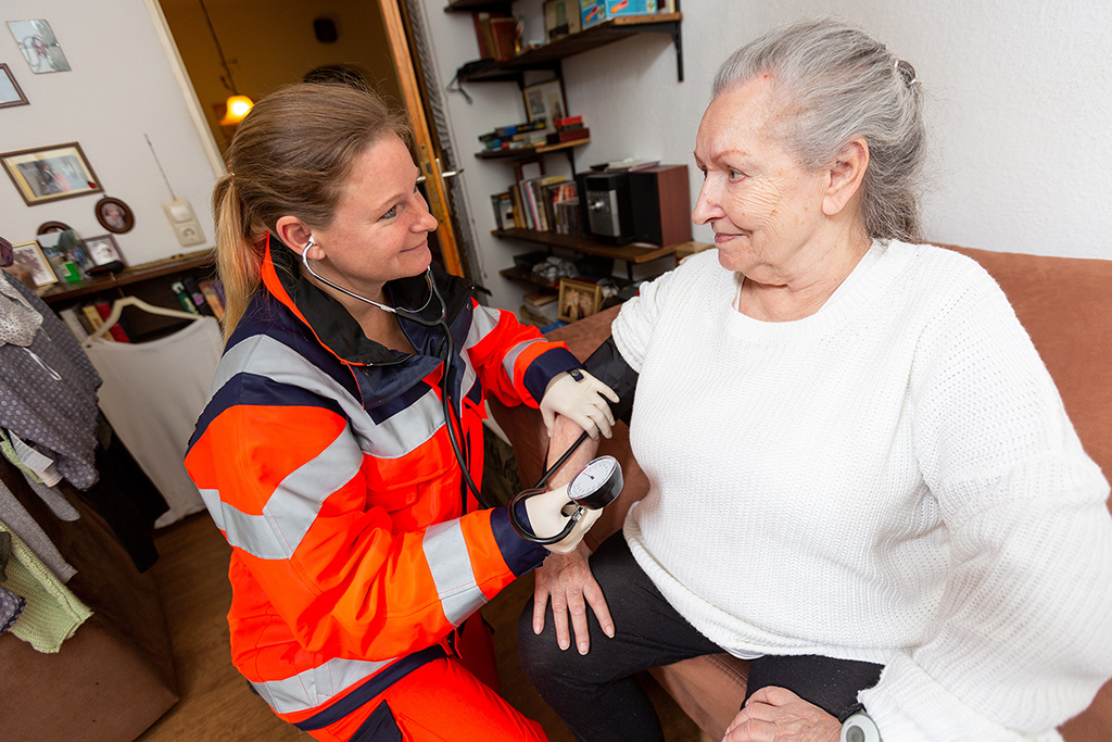 An older person is assisted by a paramedic in the home