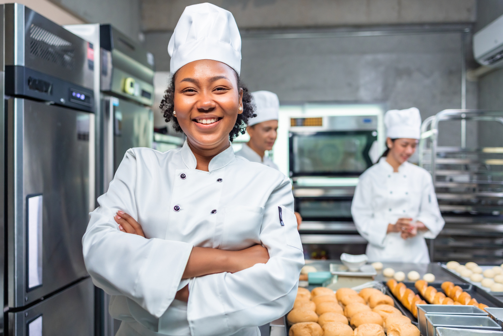 female chef standing in kitchen surrounded by baked rolls