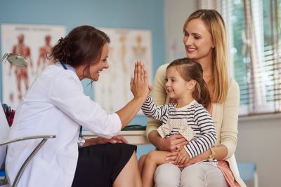 child giving a high five to female doctor