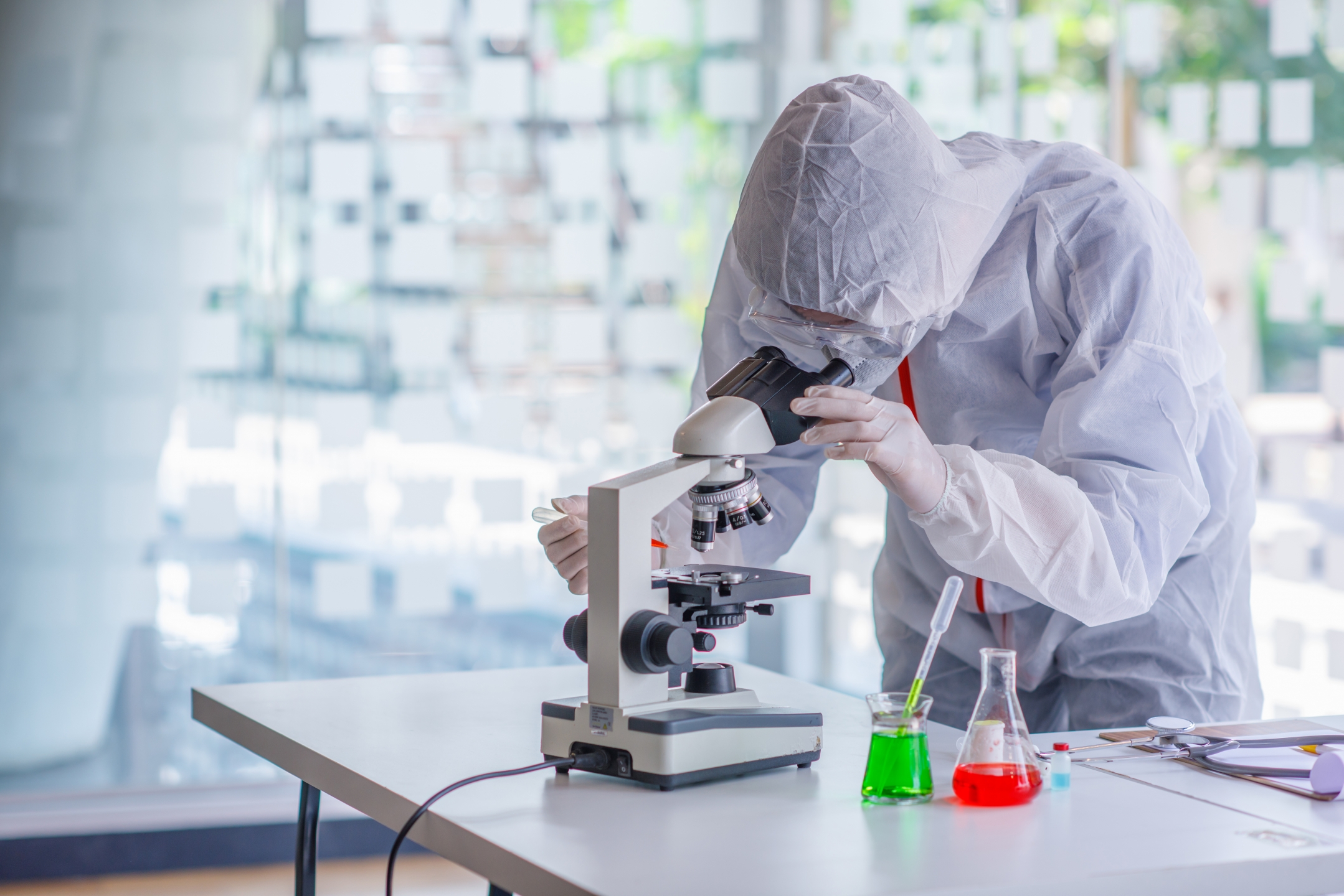 Person in a hazmat suit looking in a microscopt