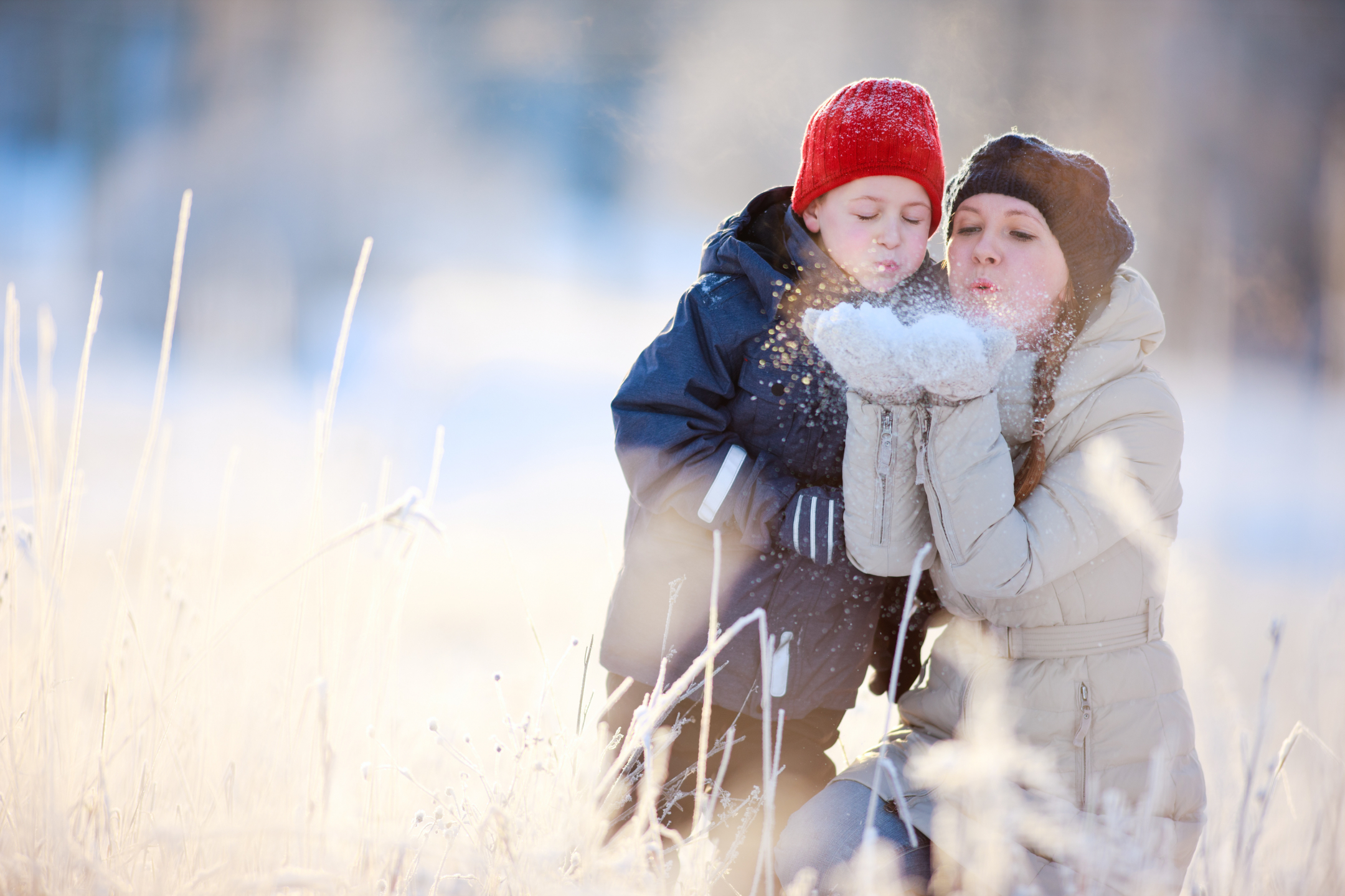 a child plays in the snow with a parent