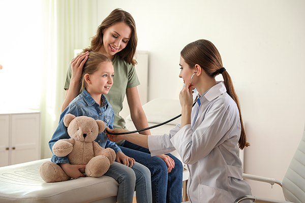 Mother and daughter visiting pediatrician. Doctor examining little patient with stethoscope in hospital