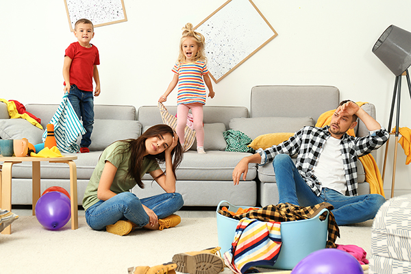 Frustrated parents and their mischievous children in messy room