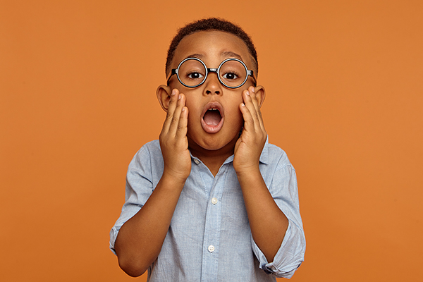 funny surprised adorable black little boy in round glasses and shirt having astonished shocked facial expression