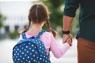 A school-aged child walks with a parent