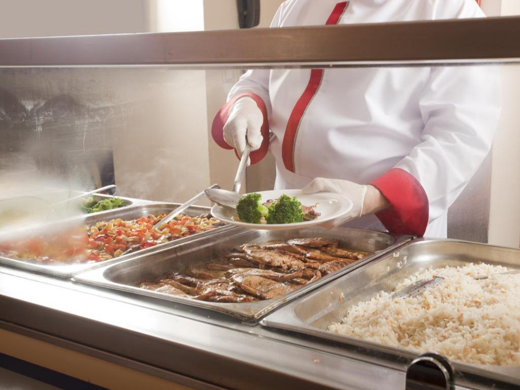 Gloved person dishing food in buffet