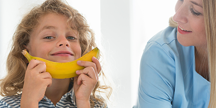 Girl and her mom smiling at a banana 