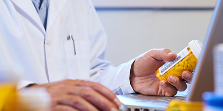 Medical provider looking at a pill bottle in front of a computer