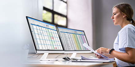 Woman working on a computer with two monitors 