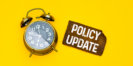 Alarm clock on yellow background with policy update text