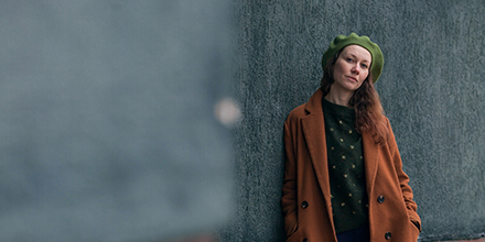 Woman standing alongside an outdoor wall.