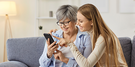A senior woman and her daughter using a cell phone.