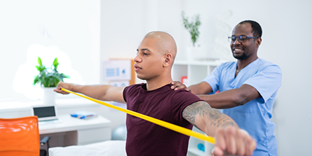 A man doing strengthening exercises with the help of a medical professional. 