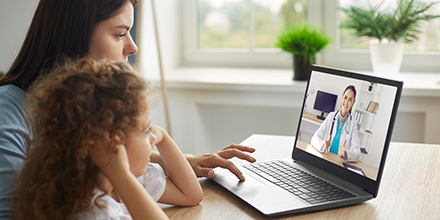 A woman and her daughter visiting with their health care provider over computer video.