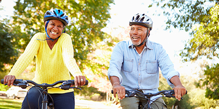 A man and woman smiling and riding bikes.