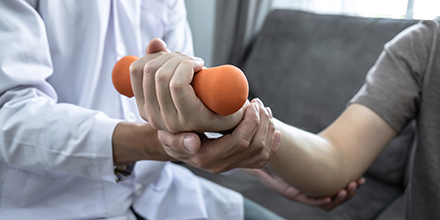 A person using a orange hand-held weight with a therapist