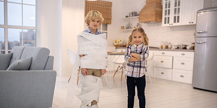 Two children wrapping each other in a roll of paper