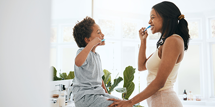 A mom and her son brushing their teeth together.