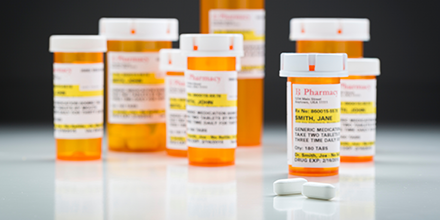 Multiple pill bottles and two tablets sitting on a surface.