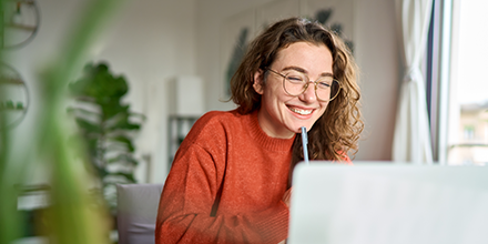 A woman smiling as she works on her computer.