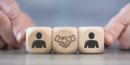 Three wooden blocks with a person icon and a shaking hands icon