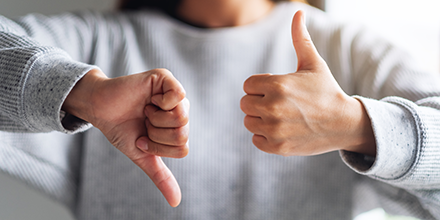 A person holding a thumbs-up and a thumbs-down.