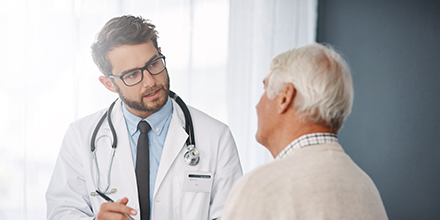 Doctor listening to an older man in a clinic room