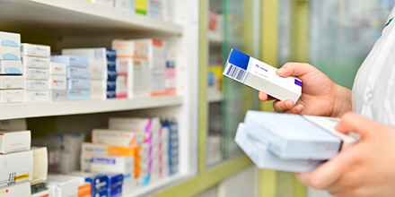 Person holding two boxes of medicine in a pharmacy