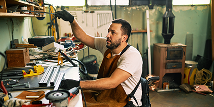 A man in a wheelchair working at a workbench.