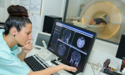 Medical worker reviews medical scans on a computer monitor