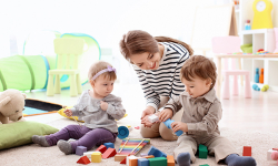 female child care provider playing with little children indoors