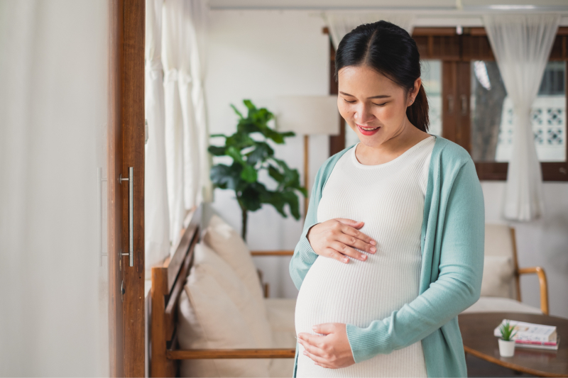Pregnant woman holding and looking down at her belly